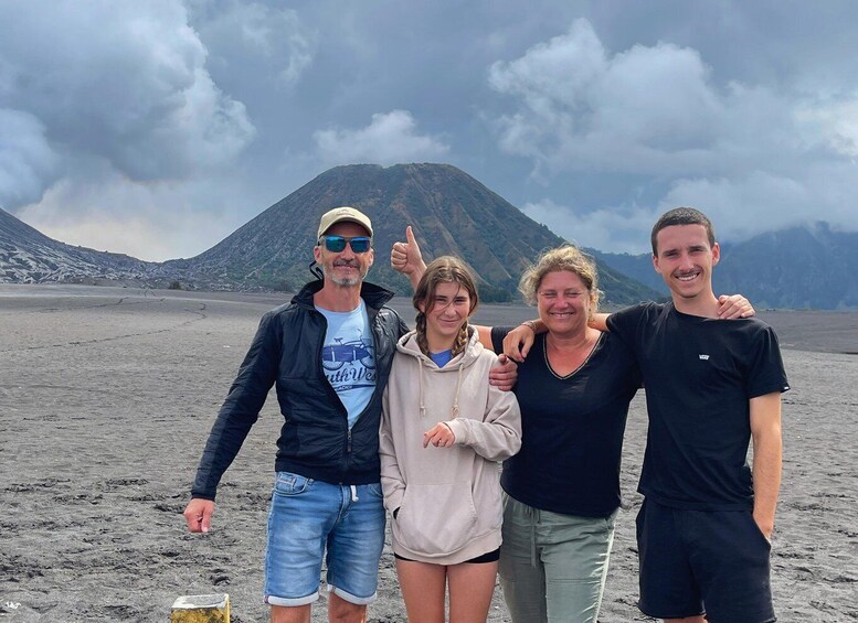 A group of people on a beach with a mountain in the background. 3