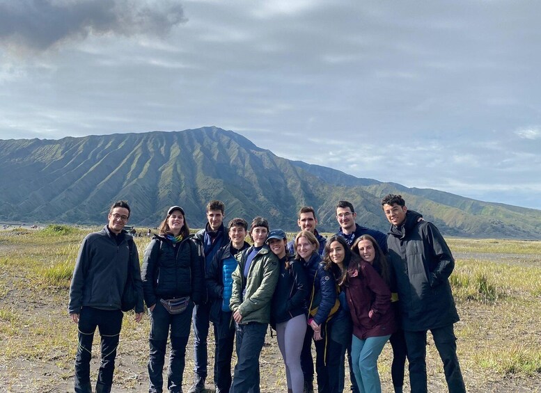 A group of people standing in a field with a mountain in the background. 2