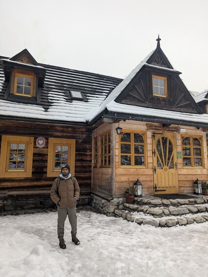 A wooden building with a snow-covered roof and a sign reading '1876 SCHRONISKO w Dol Roztok.' 3
