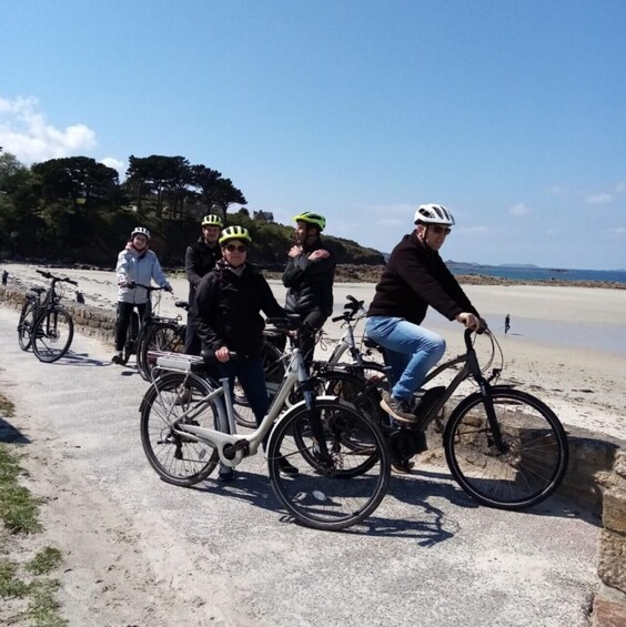 A group of people on bicycles near a beach with a clear sky. 3