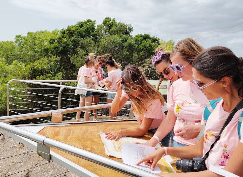 A group of people sitting on a wooden platform outdoors, some reading and others looking at a map. 4