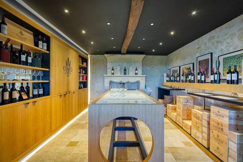 A wine cellar with wooden shelves, a central tasting area, and wine boxes. 5
