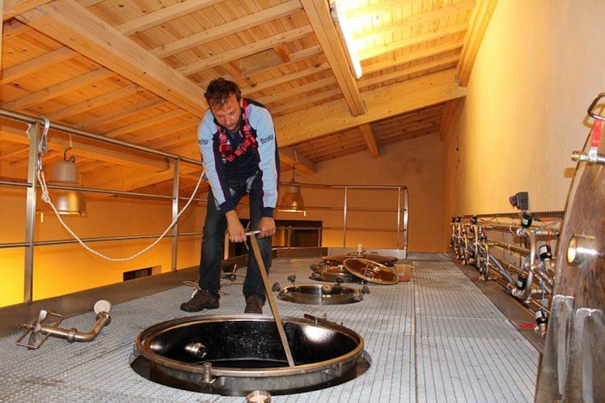 A person operating a large industrial machine in a wooden-roofed facility. 3
