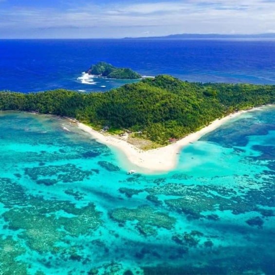 An aerial view of a tropical island with a white sandy beach, clear turquoise waters, and lush green vegetation. 1