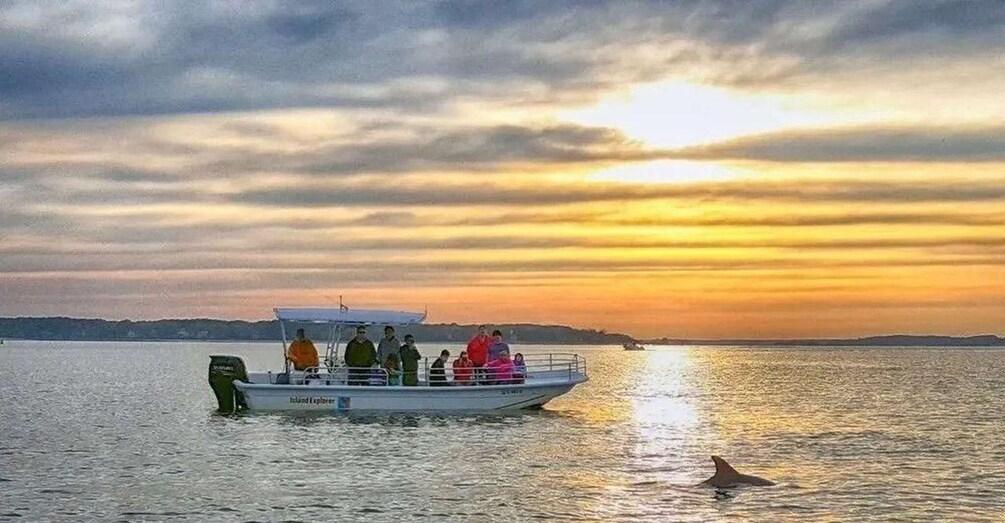 A boat with people on a calm body of water during sunset. 1
