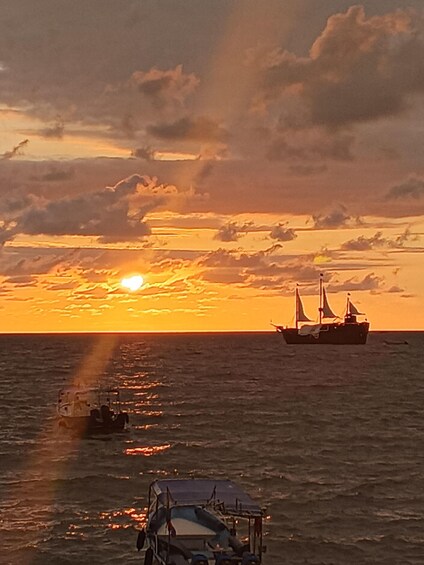 A sunset over the ocean with a ship and a small boat. 5