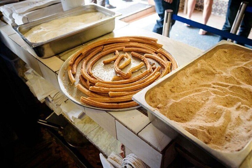 Churros arranged on a tray and a tray of powdered sugar. 4