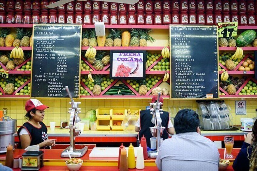 A fruit stand with various tropical fruits and a menu board. 3