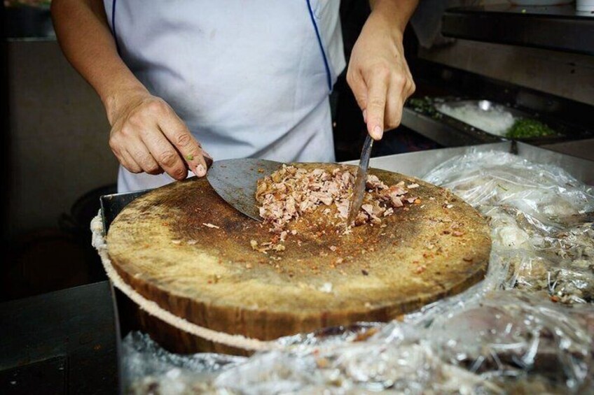 A person slicing meat on a large wooden cutting board. 4