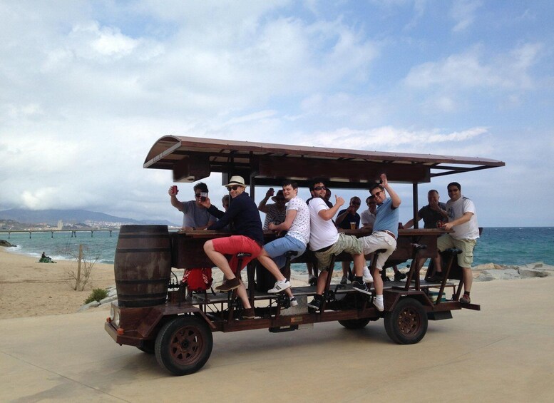 A group of people on a wooden cart with a canopy, parked on a beach with the ocean and a cloudy sky in the background. 4