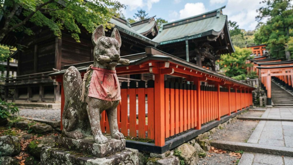 A stone statue of a dog with a pink cloth, a traditional Japanese building, and a red torii gate. 2