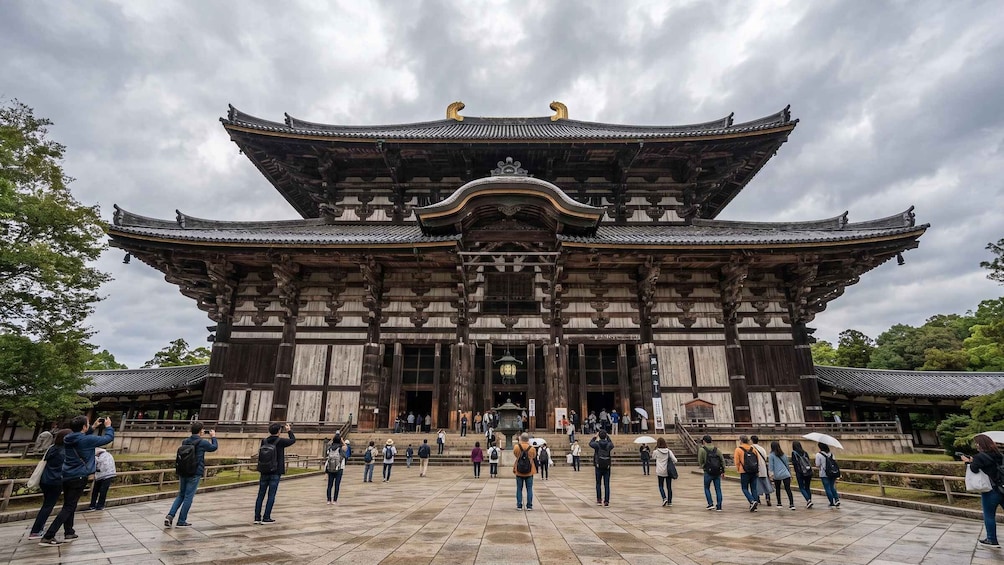 A traditional wooden building with a curved roof and golden ornaments, surrounded by visitors. 5