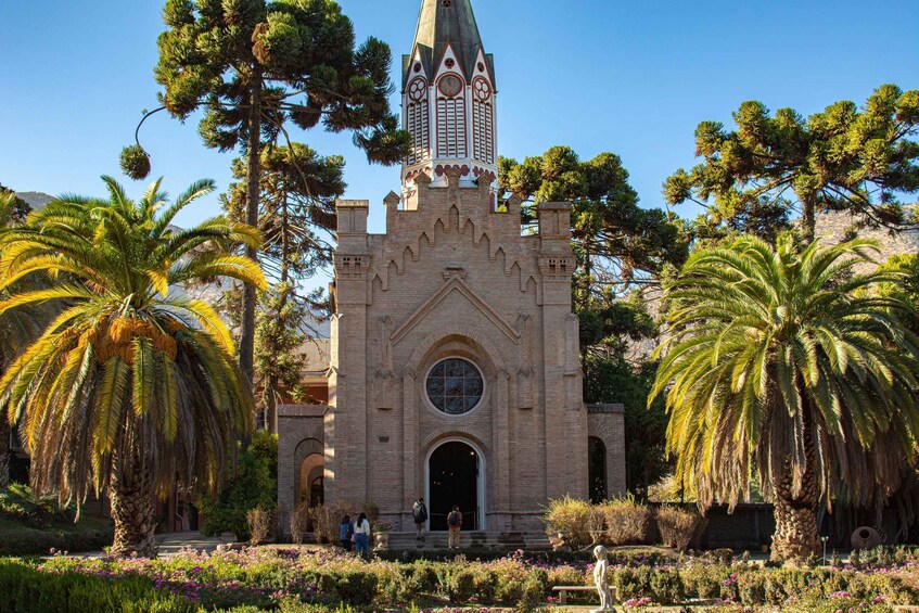 A historic building with a clock tower, surrounded by palm trees and a well-maintained garden. 4
