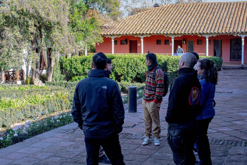 A group of people standing in a courtyard with a tiled-roof building in the background. 5