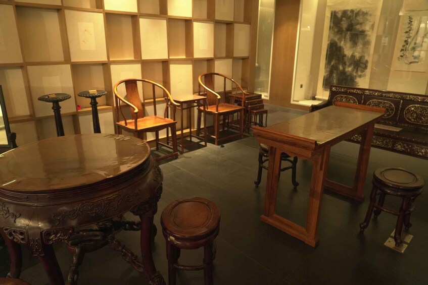 A room with a round table, several chairs, a sofa, and a decorative wall with shelves. 5