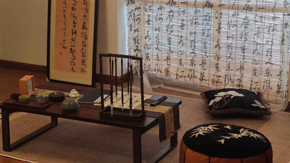 A traditional Japanese room with tatami flooring, a low table with calligraphy, a wooden chair, and a window with shoji screens. 1