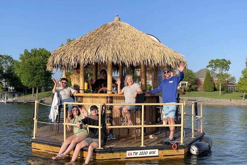 A group of people on a floating platform with a thatched roof, surrounded by water and greenery. 5