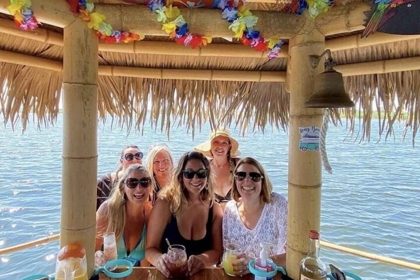 A group of people on a boat with a thatched roof and colorful decorations. 3