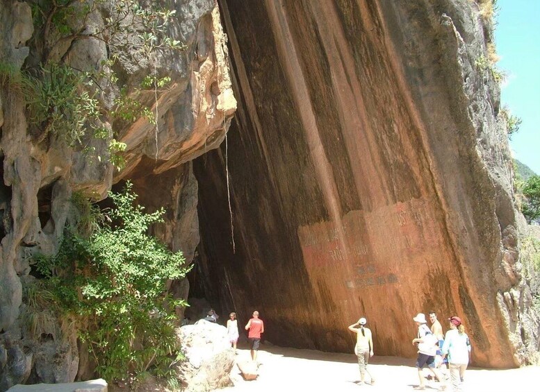 A large rock formation with people standing in front of it. 2