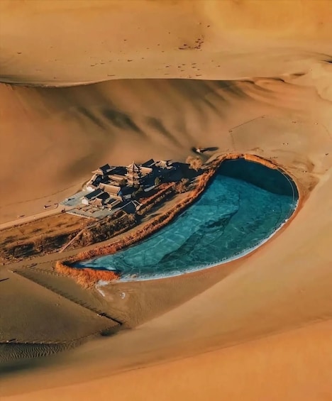 An aerial view of a desert oasis with a swimming pool and traditional buildings. 1