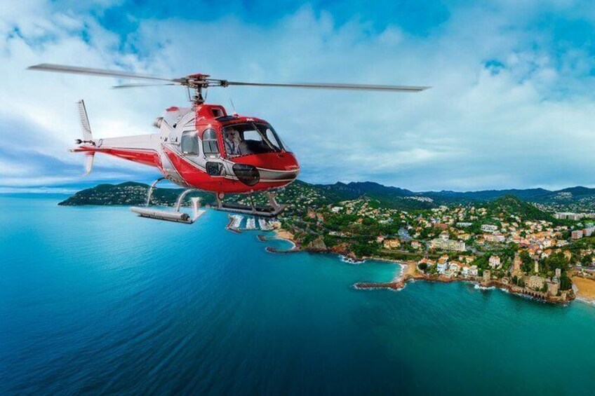 A red helicopter flying over a coastal town with a clear sky. 3