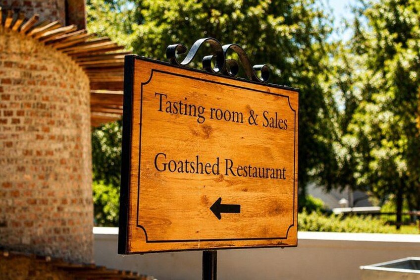 A wooden sign with a black arrow pointing left, indicating the direction to the Tasting room & Sales and Goatshed Restaurant. 2