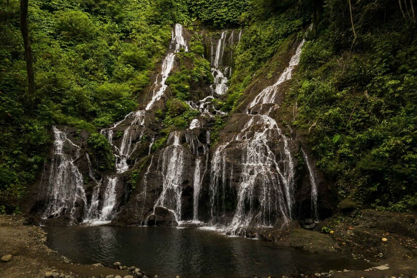 A waterfall cascading over rocky terrain surrounded by dense green foliage. 2