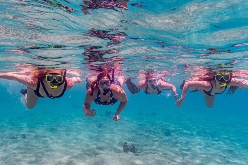 Three people snorkeling underwater in clear blue water. 5