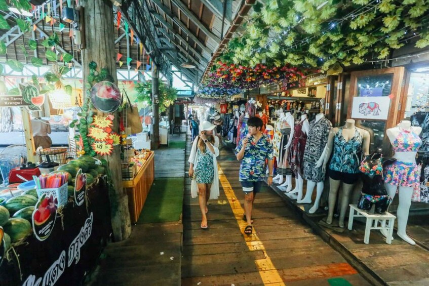 A market with wooden stalls, hanging plants, and mannequins displaying clothing. 2