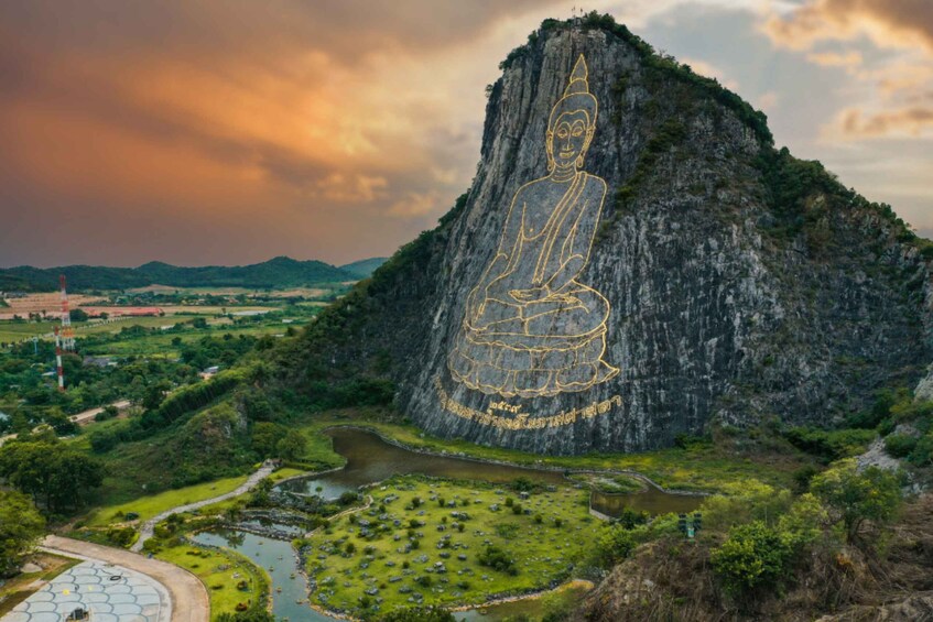 A large Buddha statue carved into a cliff, surrounded by a landscaped garden and a river. 1