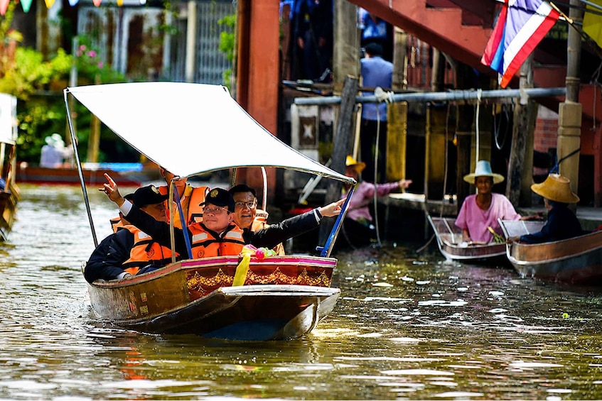 A traditional boat with passengers, water, and buildings in the background. 2