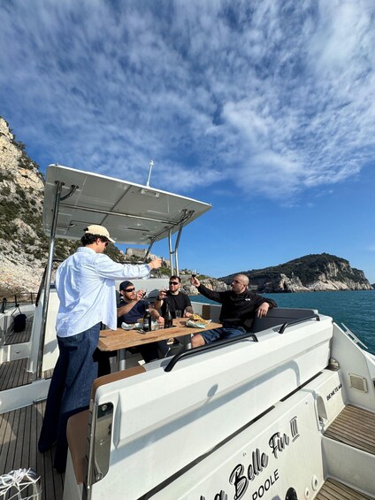 A group of people on a boat with a rocky coastline and cliffs in the background. 5