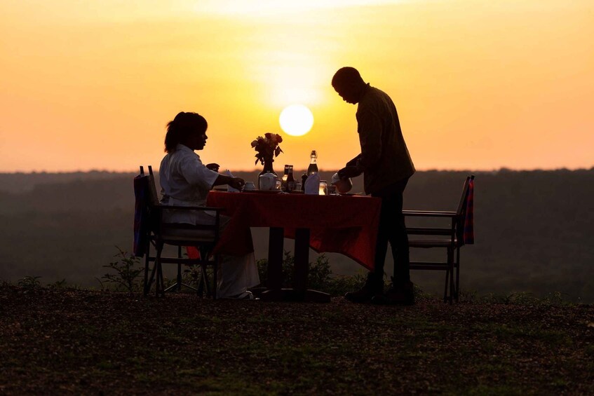A couple dining at a table with a sunset in the background. 3