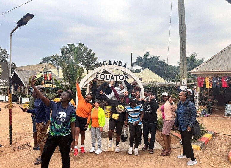 A group of people posing in front of a sign that reads 'Uganda Equator.' 5