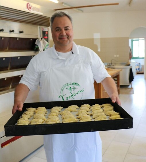 A person in a white chef's uniform holding a tray of pastries. 3