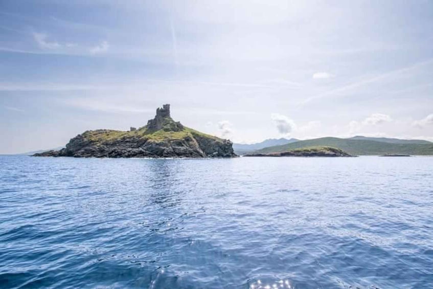 A rocky island with a tower in the middle of a calm sea, surrounded by clear skies. 3