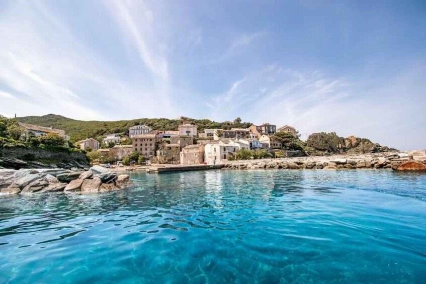 A coastal town with buildings on a hillside, calm blue waters, and clear skies. 5