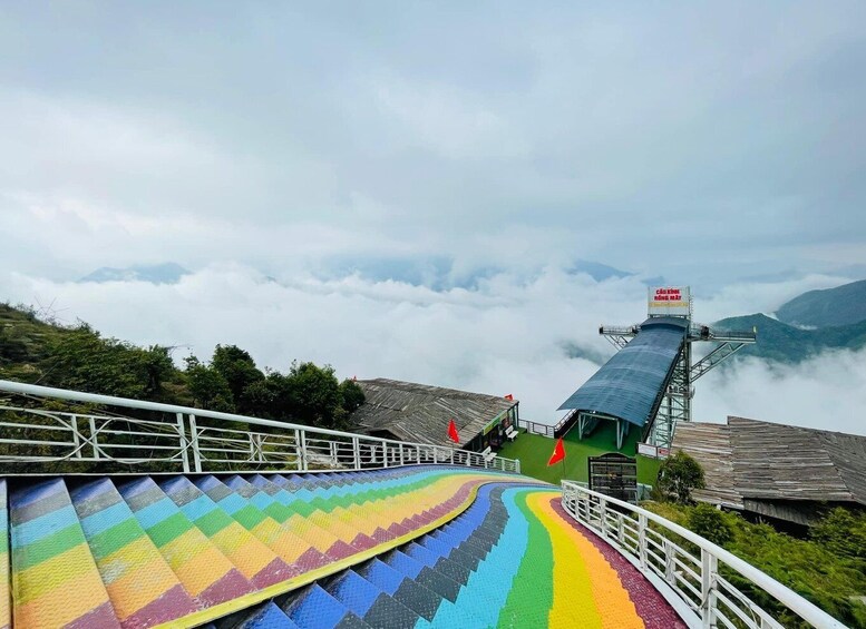 A colorful pedestrian bridge with a rainbow pattern, leading to a viewpoint with a sign reading 'Cà Khẩu Kinh Rộng Mặt.' 3