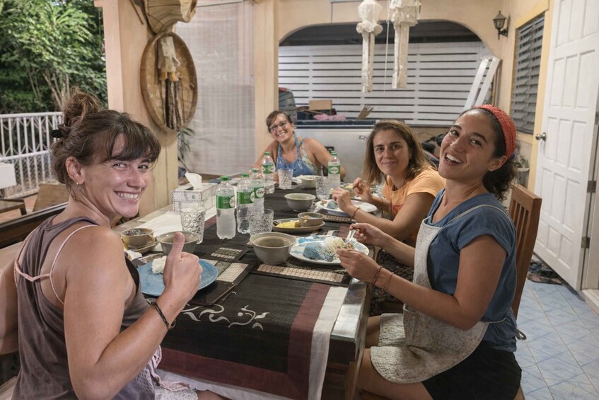 A group of people dining at an outdoor table with various dishes and drinks. 4