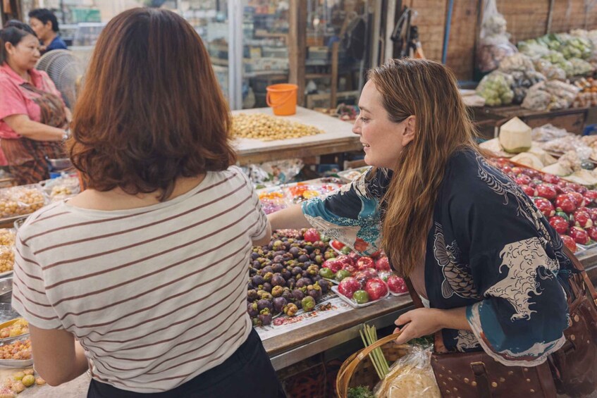 Two people at a market stall with various fruits and vegetables. 5