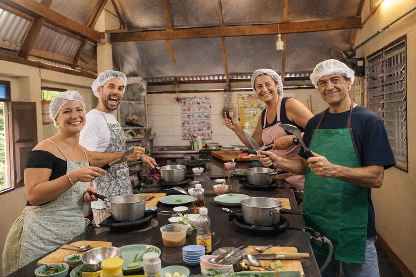 A group of people cooking in a rustic kitchen with wooden beams and a tiled backsplash. 1