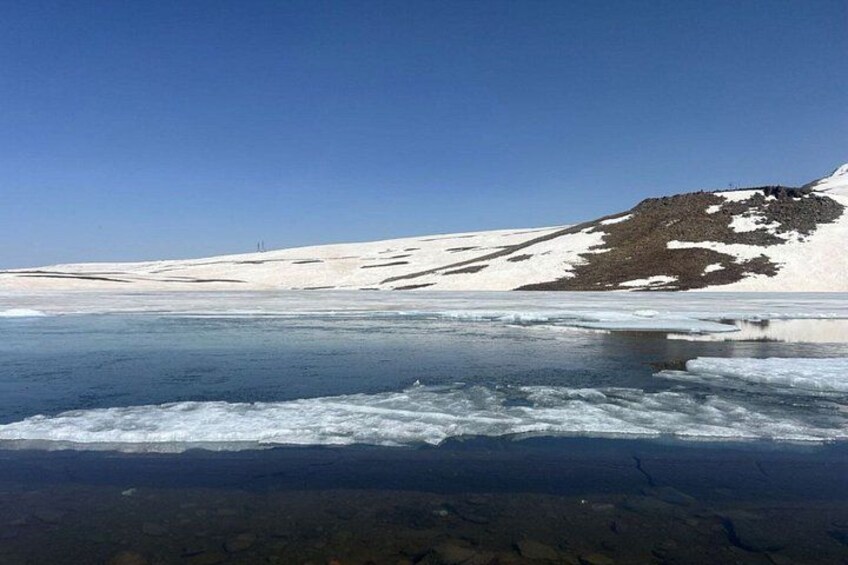 A frozen lake with snow-covered mountains in the background. 3