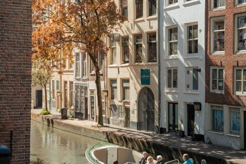A canal with buildings on one side and a tree with autumn leaves. 4