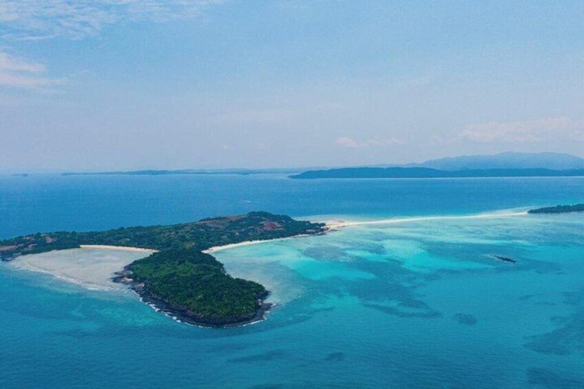 An aerial view of a tropical island with clear turquoise waters, a sandy beach, and lush greenery. 2