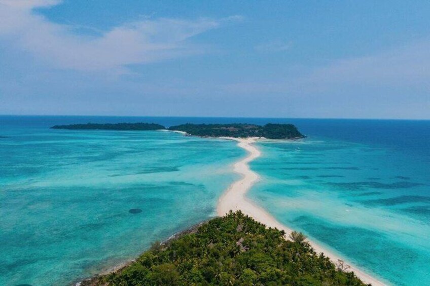 A turquoise sea with a sandy beach and a small island in the distance. 3