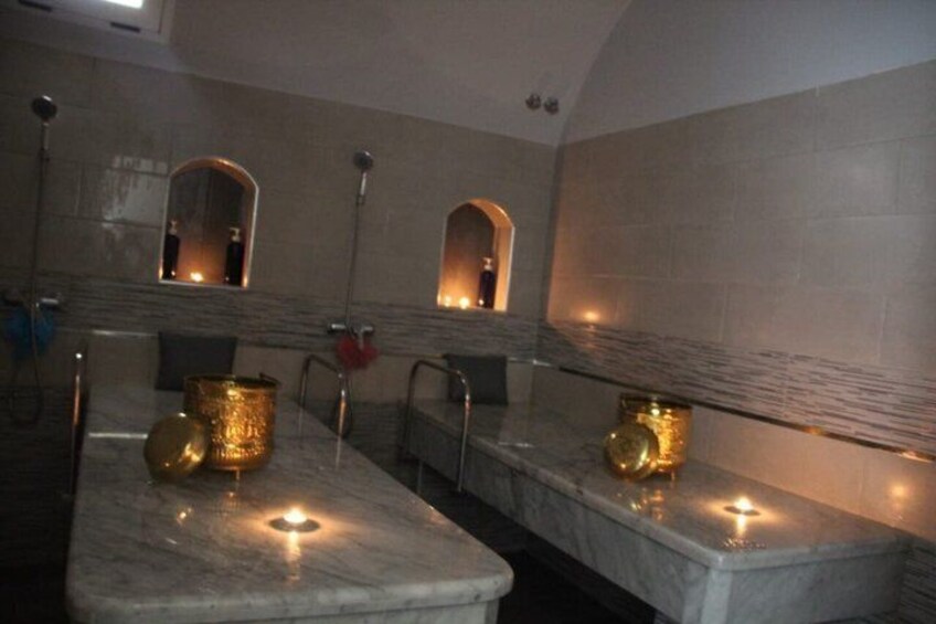 A bathroom with marble countertops, gold-colored fixtures, and wall-mounted mirrors. 1