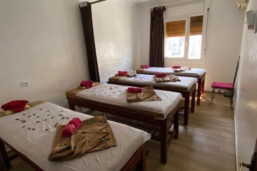 A room with three wooden beds, each with a white mattress and red pillows, and a mirror on the wall. 5