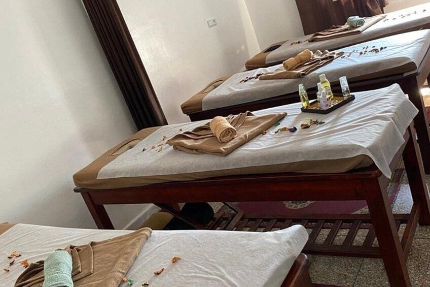 A room with massage tables, towels, and bottles. 2