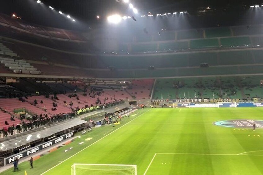 A large stadium with empty stands and a well-maintained grass pitch. 2