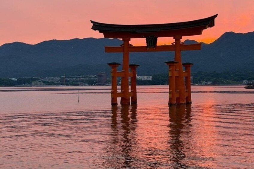 A torii gate in water with mountains in the background. 1